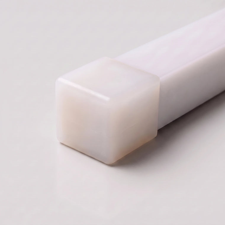 Close-up of a closed opal silicone end cap for 15x15mm LED neon flex on a light grey background