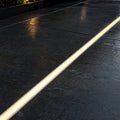 LED floor profile set flush into dark paving, lit warm white at dusk