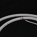 Unlit white horizontal-bend neon flex showing cut marks and red-black two-wire lead