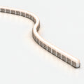 Close-up of a bendable aluminium mounting profile with glowing white LED neon flex installed in an S-shaped curve, on a pale grey background