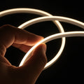 Hand holding illuminated warm-white mini neon flex — product reference