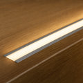 Recessed LED profile installed flush in oak surface lit warm white