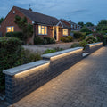 Pale-yellow RGB mixed light beneath all three coping sections along a UK driveway