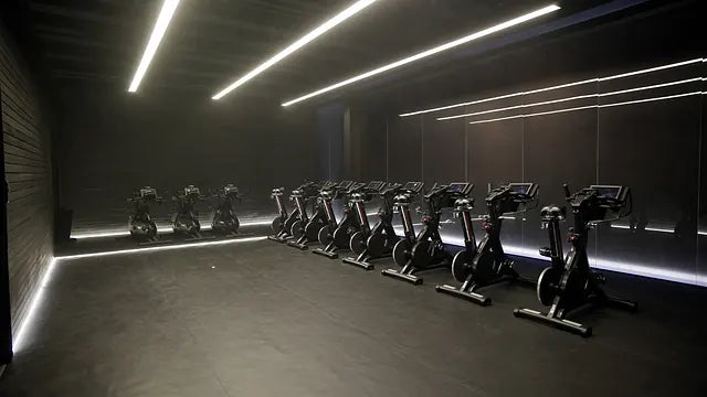 Professional indoor cycling studio with continuous architectural LED lighting and mirrored walls