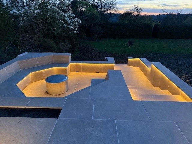Twilight reveal of the hex seating well showing the recessed warm white neon flex glowing along the marble walls