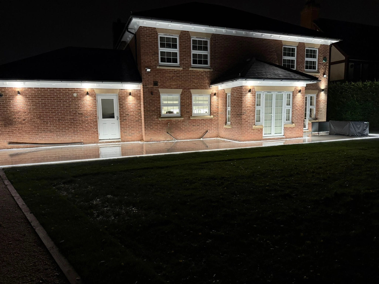 Wider patio view at night with eaves lighting and ground-line strip both visible