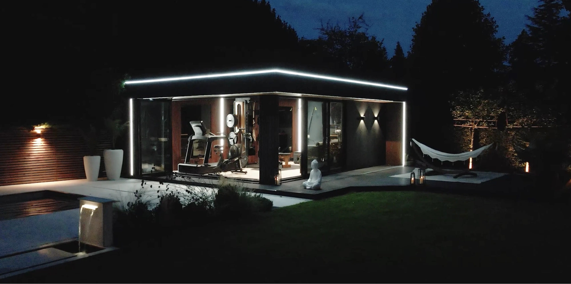 Garden room lit at night, IP67 neon flex tracing the roofline and warm COB interior glowing through the glazing