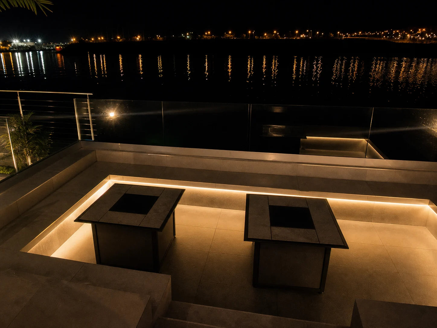 Warm white neon flex recessed under the seating and step of a waterside terrace at night