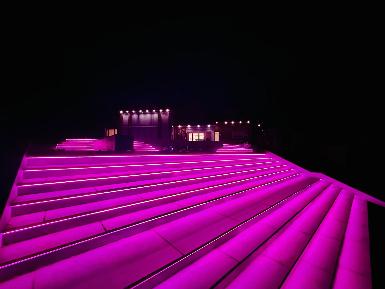 Low angle shot from below the steps, magenta RGB COB colour, showing the dramatic perspective of the run