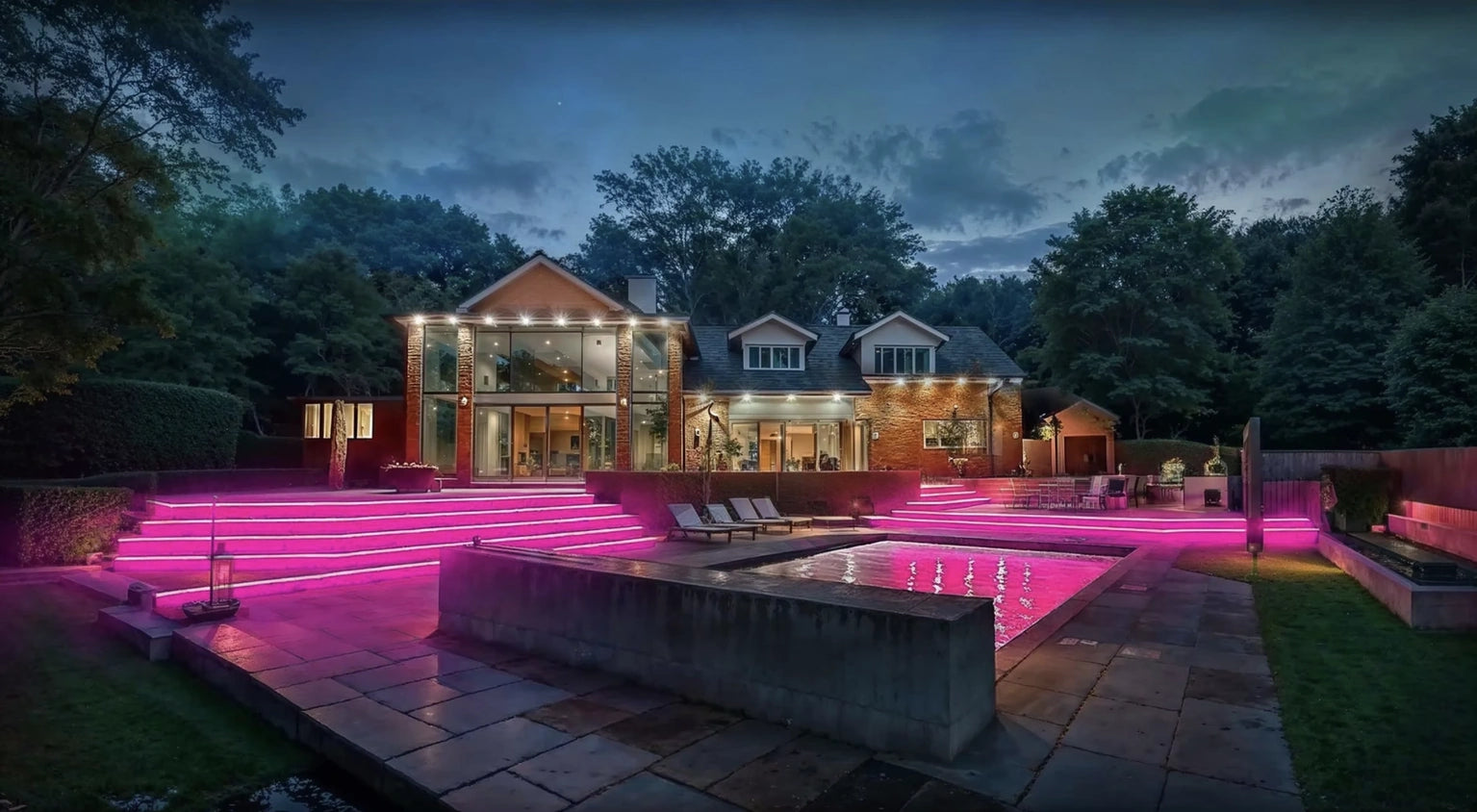 Colour-change LED lighting on the step risers and fountain pool of a private terrace at dusk