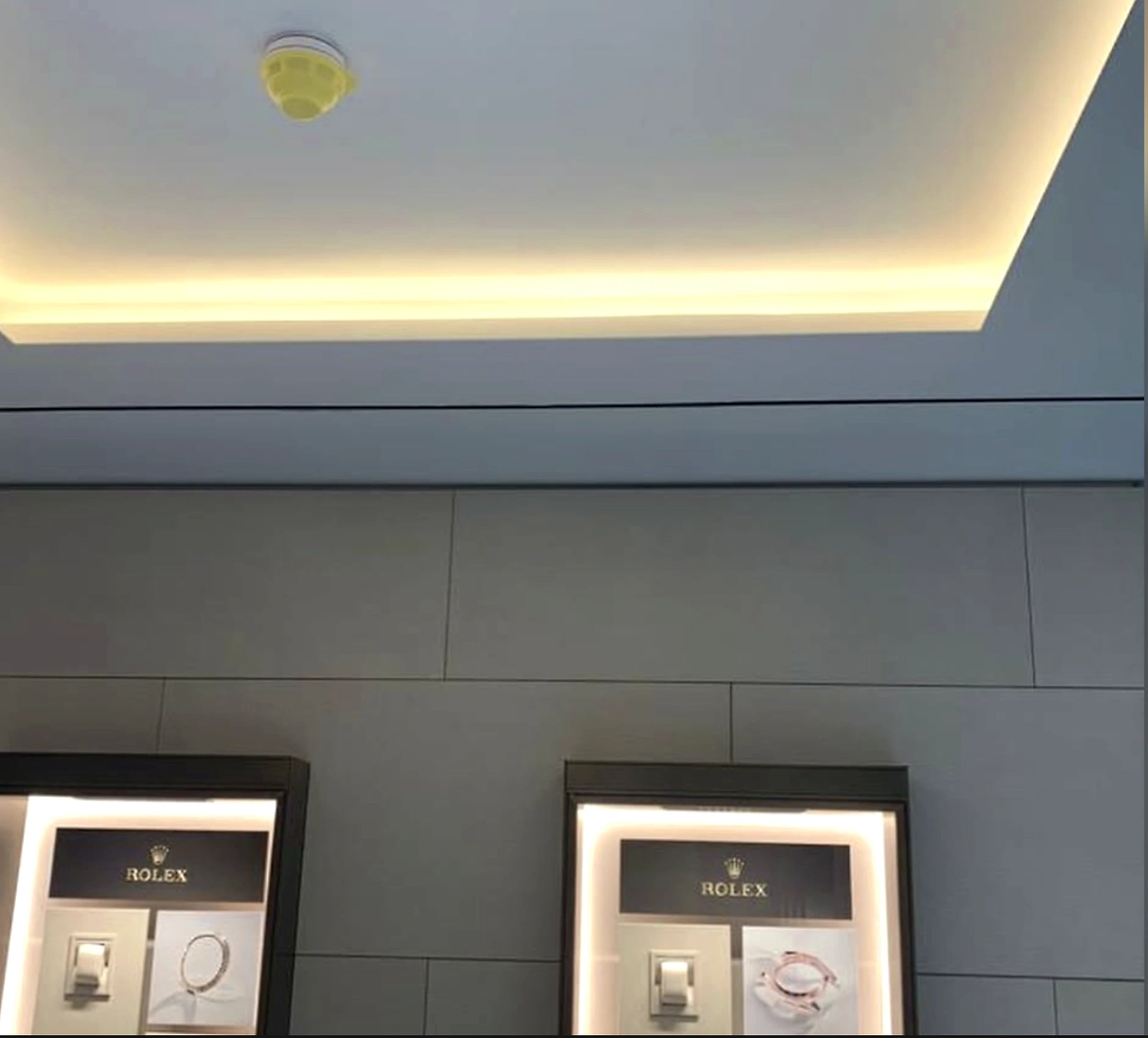 Rolex London display wall with ceiling cove lighting and illuminated watch cabinets